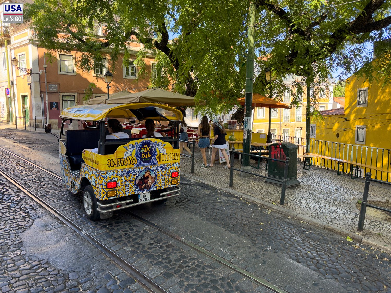 Bunt bemaltes Tuk-Tuk an einer Straßenbahnhaltestelle in der Alfama