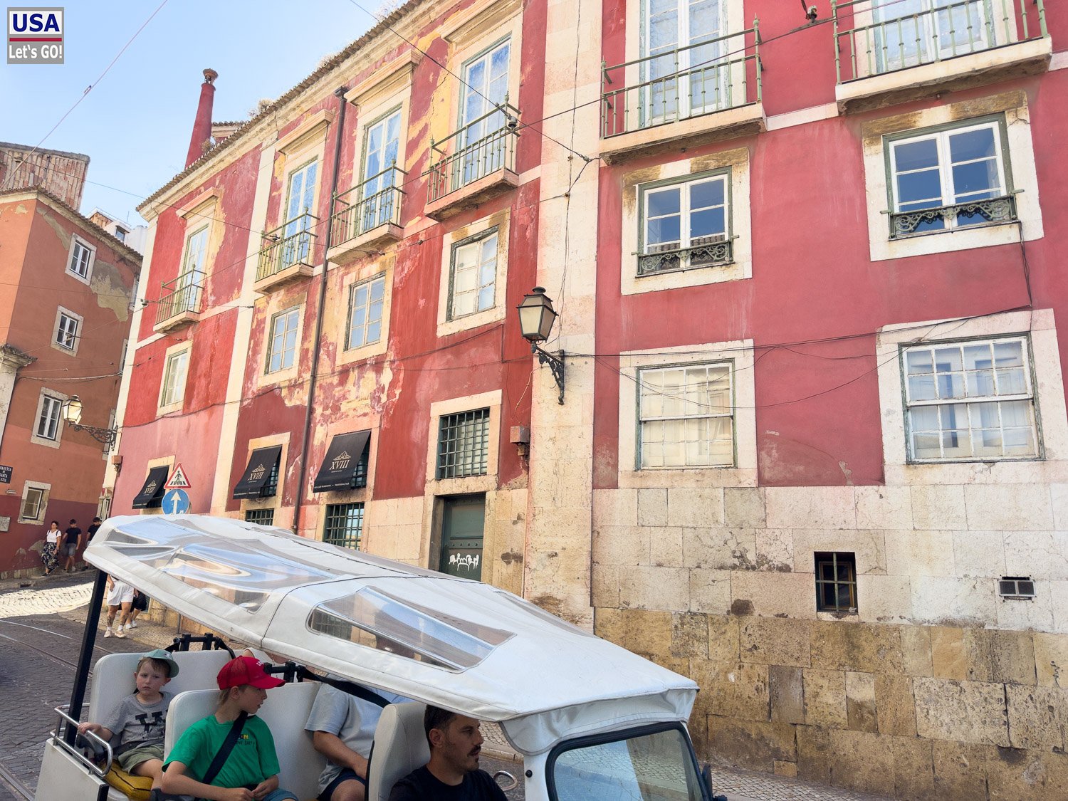 Rote Hausfassade in der Alfama, davor ein Tuk-Tuk
