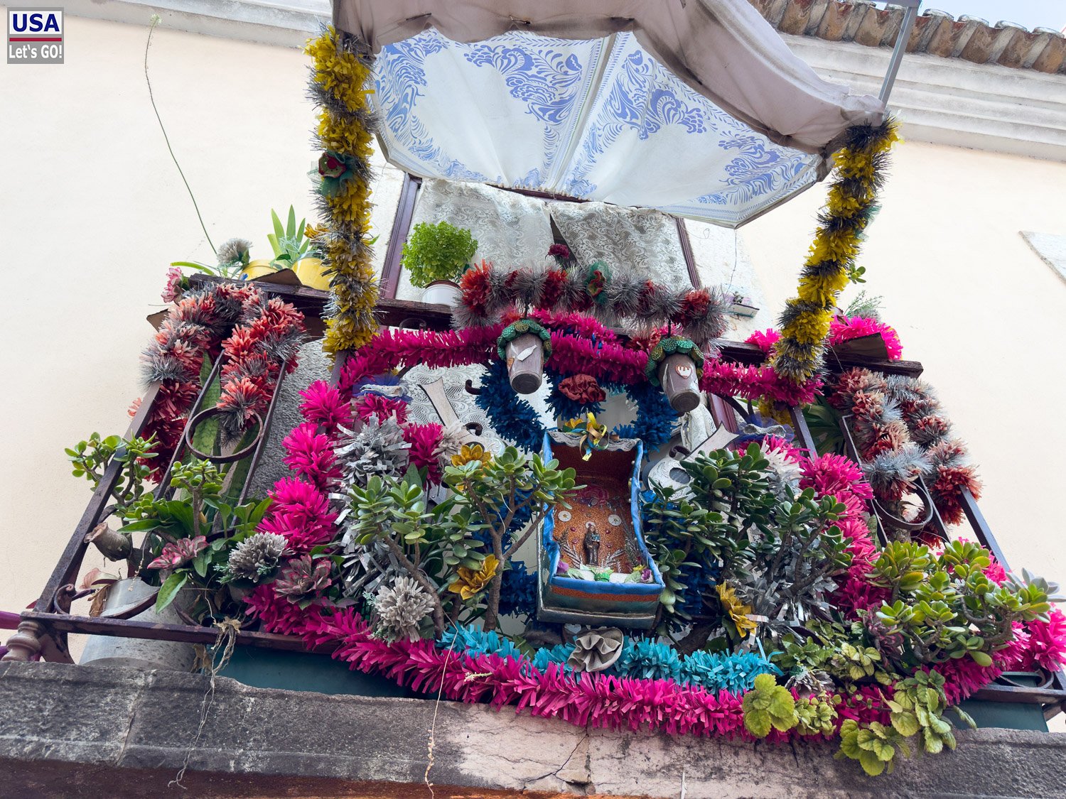 Mit Blumen geschmückter Heiligenaltar an einer Hauswand
