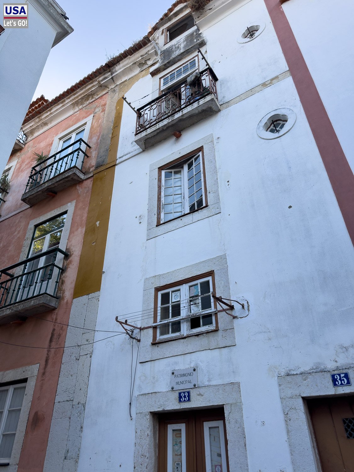 Weißes Haus mit kleinen Balkonen in einer Gasse der Alfama