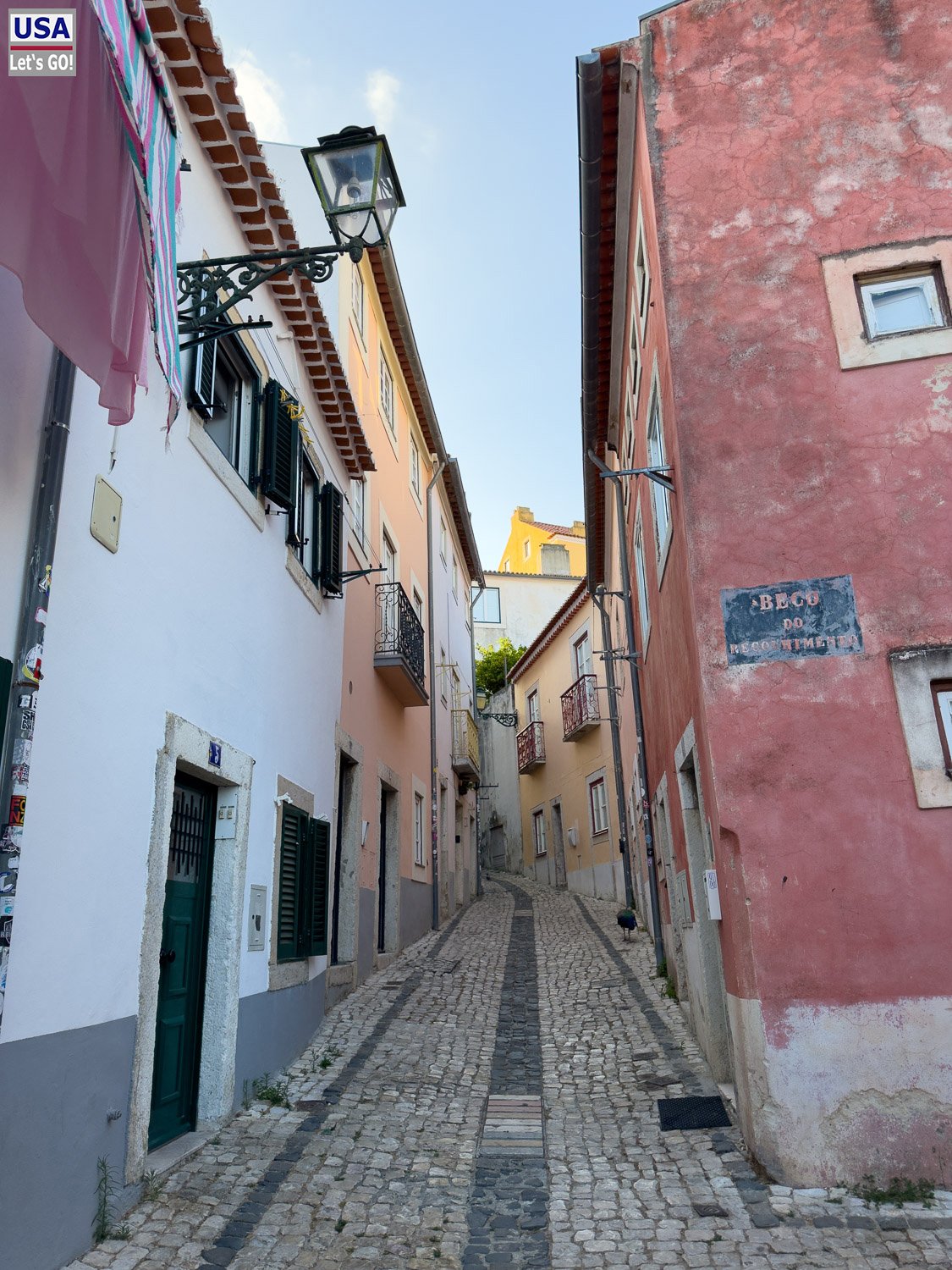 Enge Gasse mit Laterne und roter Hauswand in der Alfama