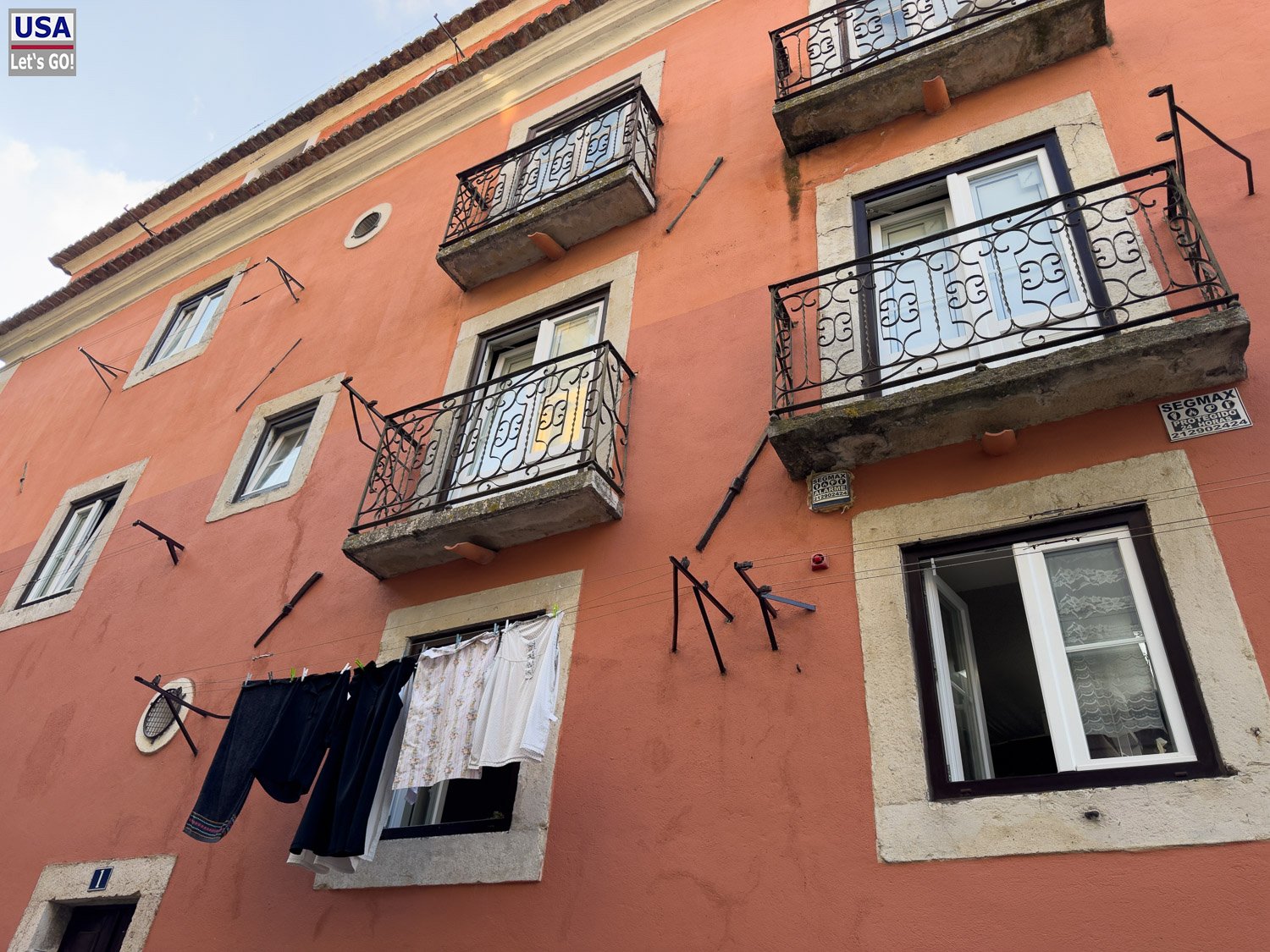 Orangefarbene Hausfassade mit Wäsche am Balkon