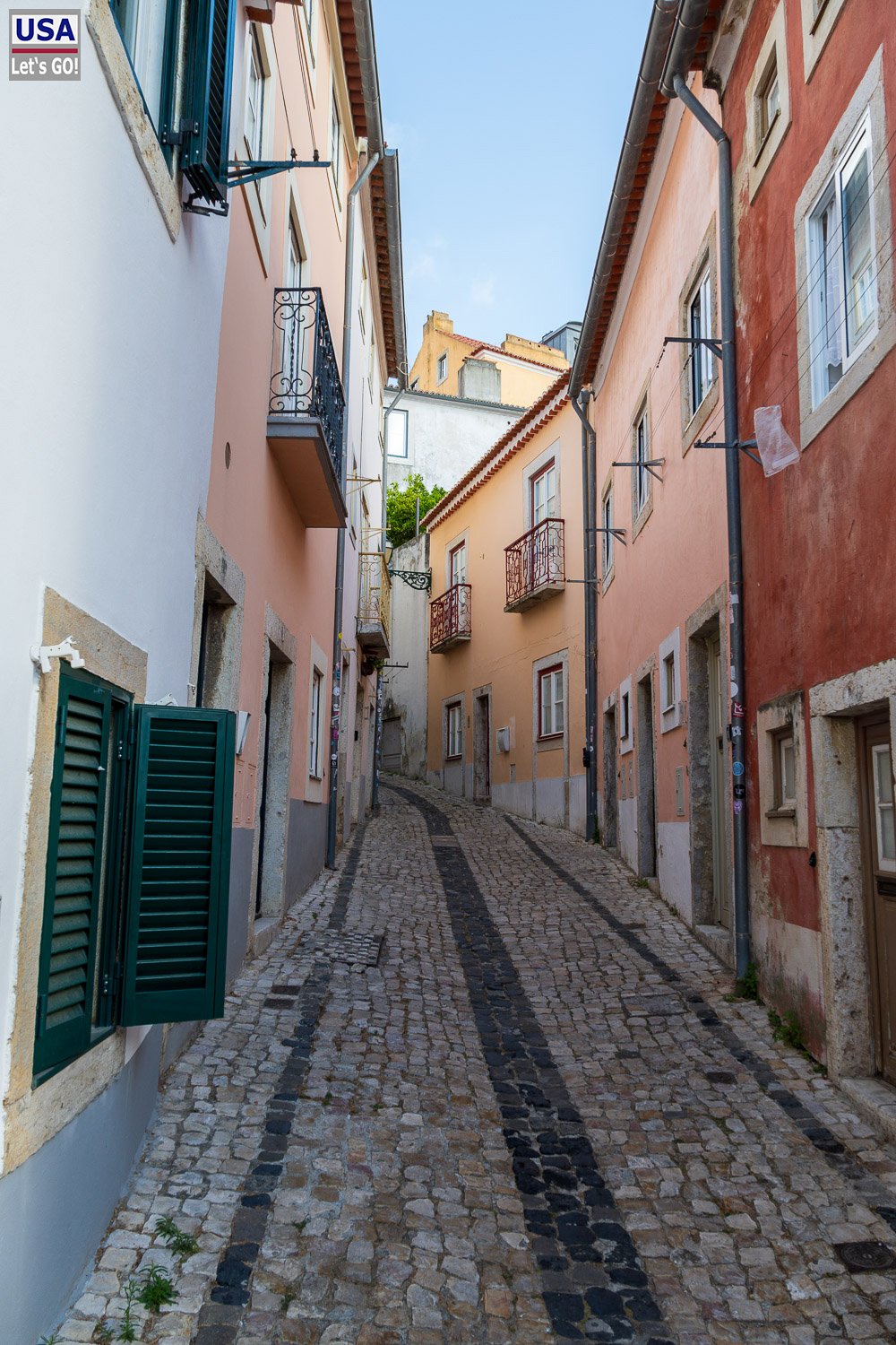 Kopfsteinpflastergasse mit grünen Fensterläden in der Alfama