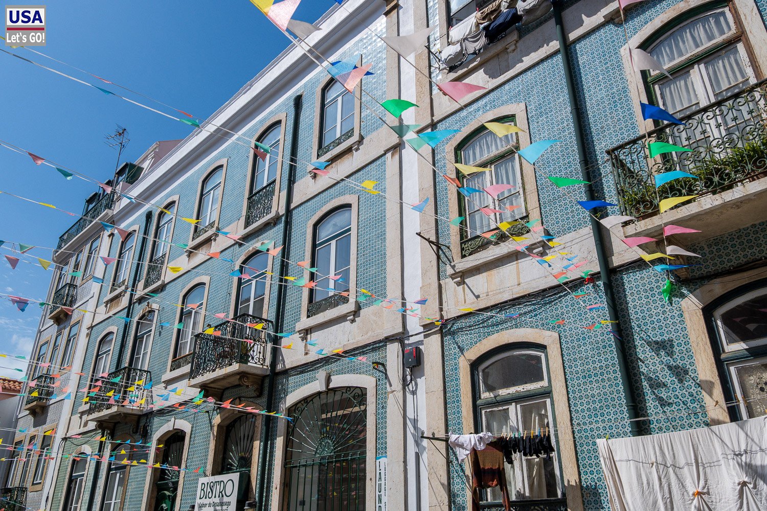 Blau gekachelte Häuser mit Wimpelketten in der Gasse