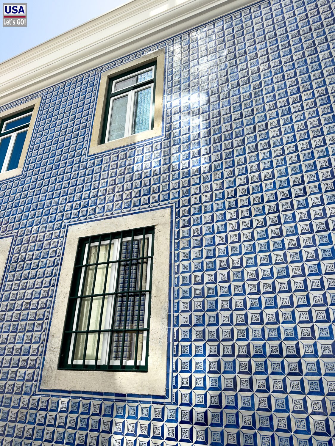 Blau gekachelte Hausfassade mit vergittertem Fenster