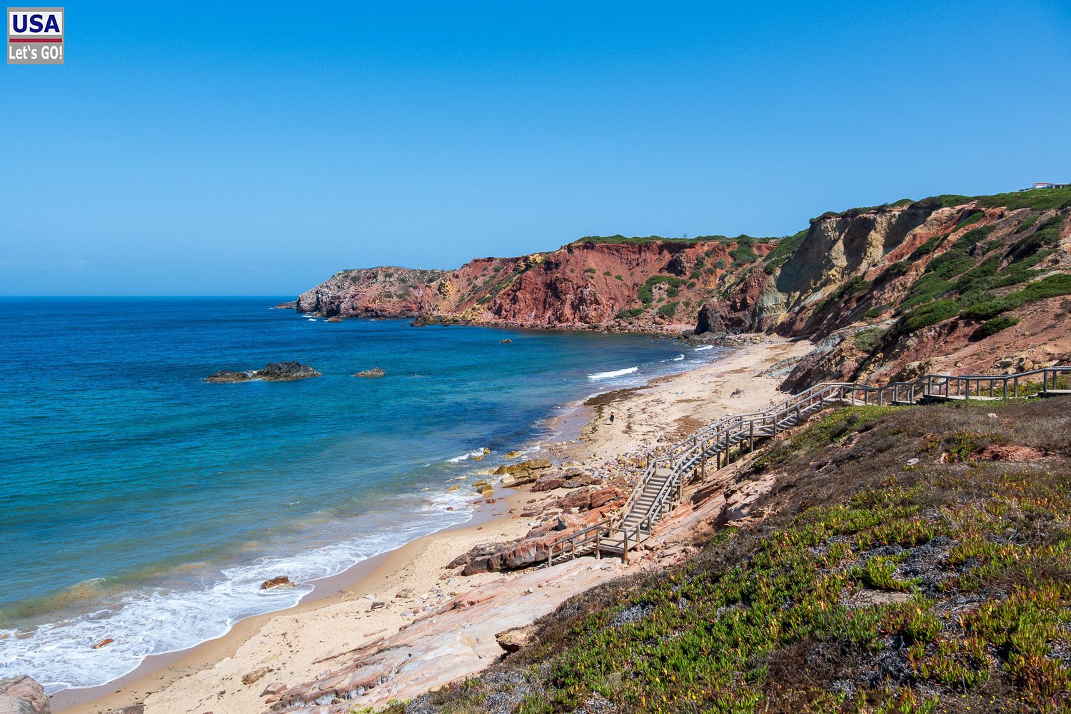 Rötliche Klippen und wilder Strand neben der Praia do Amado